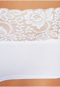 Bijela čipkasta bralette sa cvjetnim uzorkom duž gornjeg ruba, sa mekim, glatkim materijalom i delikatnim rubom na dnu.