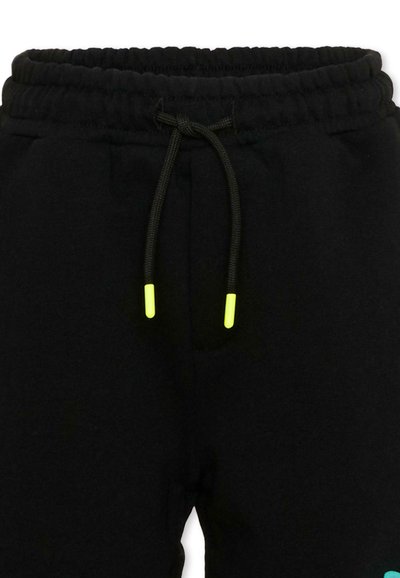 Pantalon de survêtement noir avec taille élastique et cordon de serrage noir comportant des embouts jaune vif, vu de face au niveau de la taille.