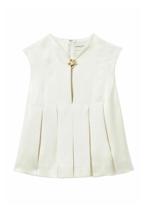 Tops sans manches couleur crème avec un design plissé, présentant un décolleté en V et un ornement floral doré au niveau du col. Texture de tissu lisse.