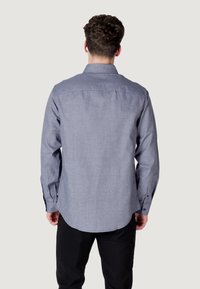 Camicia a maniche lunghe di colore azzurro chiaro con motivo a griglia, realizzata in tessuto tessuto. Presenta un colletto classico e polsini con bottoni. Vista posteriore semplice.