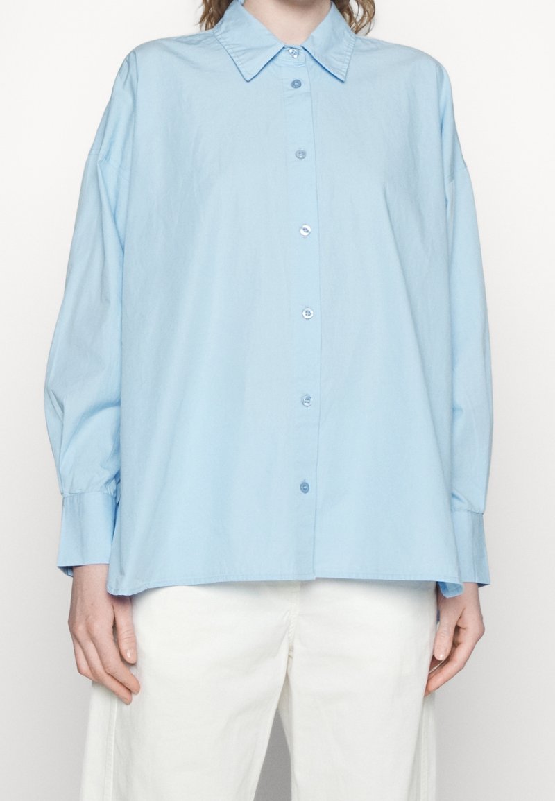 Camicia azzura chiaro button-up in cotone, con colletto, maniche lunghe e vestibilità comoda. Tessuto liscio con dettagli sui bottoni.