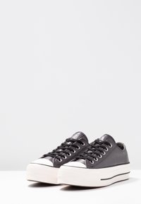 Svarta läder sneakers i låg modell med vita gummisulor, rund tå och kontrasterande svarta snören. Har en texturerad bakpanel och logodetalj.