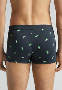 Navyblaue Boxershorts mit einem verstreuten Dollar-Muster in Grün. Hergestellt aus einem glatten, dehnbaren Material für zusätzlichen Komfort.