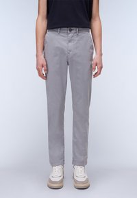 Grå, tapered chinos med en glat stof, knaplukning og forlommer, parret med lyse sneakers med beige detaljer.