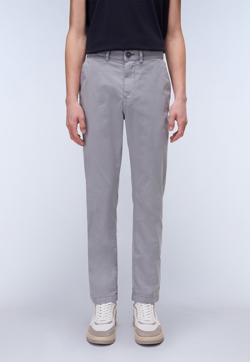 Graue, tapered Chinos aus glattem Stoff, mit Knopfverschluss und Vordertaschen, kombiniert mit hellen Sneakers mit beigen Akzenten.