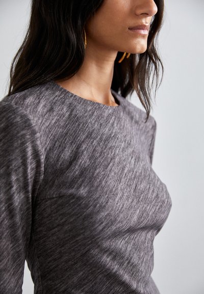 Gray, textured long-sleeve top with a round neckline, featuring a subtle heather pattern, shown worn at shoulder and neckline.