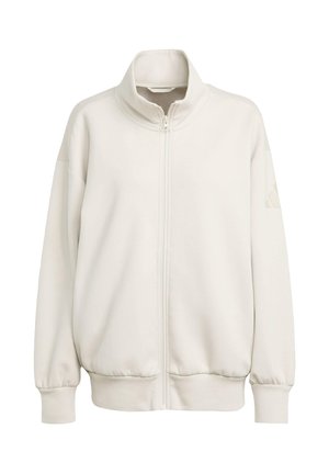 Krémová mikina na zip s vysokým límcem, spadlými rameny, žebrovanými manžetami a lemováním, vyrobená z hladkého materiálu, s jemným detailem loga na rukávu.