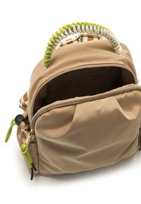 Mochila de nylon beige con un asa trenzada verde y blanca, compartimentos con cremallera, bolsillos laterales con detalles metálicos y un acabado texturizado.