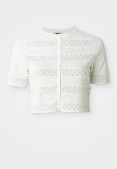Cardigan blanc à manches courtes avec des fermetures à boutons en perles et des rayures en maille horizontale ornées de petites perles sur le devant et les manches.