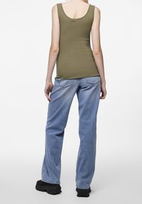 Olivově zelený žebrovaný top bez rukávů spárovaný s světle modrými rovně střiženými džíny, které mají uvolněný střih a jemné blednutí. Černé robustní obuv.