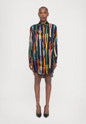 Robe à manches longues en tissu noir ornée d'un motif vif de fermetures éclair colorées. Boutonnage sur le devant avec un col et un ourlet arrondi.