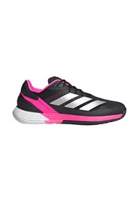 Chaussure de course noire et rose avec des rayures blanches, des lacets noirs et le texte "Defiant Speed" sur le côté, vue de l'extérieur.
