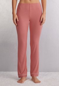 Lichtroze katoenen pyjamabroek met een elastische tailleband, uitlopers en een contrasterende witte bies bij de enkel. Zachte, gladde textuur.