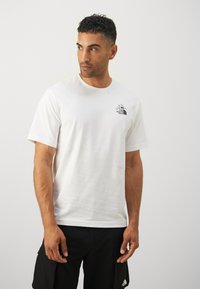 Hvid bomulds T-shirt med et sort bjerglogo på brystet. Korte ærmer og rund halsudskæring. Glat tekstur og afslappet pasform.