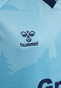 Blå sportströja i tyg med en mörkblå stiliserad bi-logotyp ovanför ordet "hummel" nära kragen.