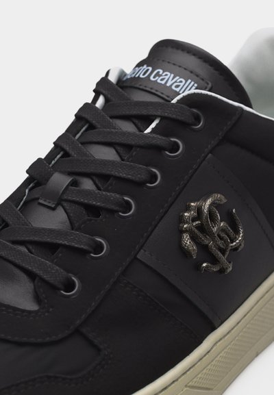 Μαύρο δερμάτινο αθλητικό παπούτσι με μαύρα κορδόνια, μεταλλικό έμβλημα φιδιού στο πλάι, λευκή επένδυση και λευκή-καφέ ελαστική σόλα.