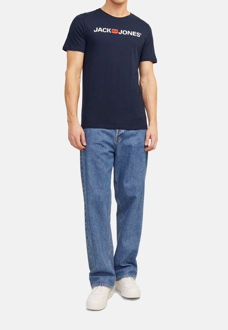Marineblaue Baumwoll-T-Shirt mit kurzen Ärmeln, ausgestattet mit einem weißen Logo-Druck "JACK & JONES". Kombiniert mit hellblauen geraden Jeans und weißen Sneakern.