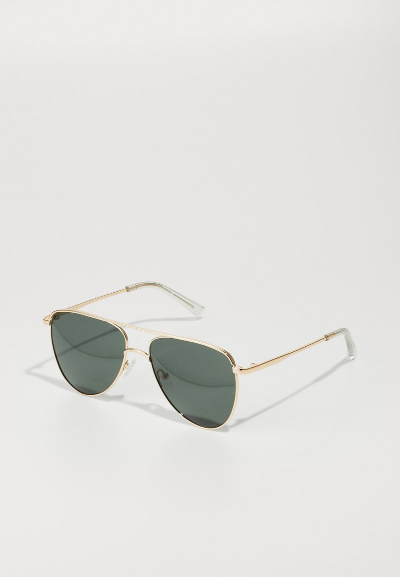 Gold metal sunglasses with dark green lenses, featuring a slight cat-eye shape and clear plastic temple ends for added comfort.