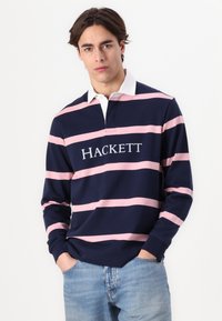 Tengerészkék, hosszú ujjú csíkos póló, rózsaszín csíkokkal, fehér gallérral és elől "HACKETT" logóval. Pamut anyag, normál fazon.