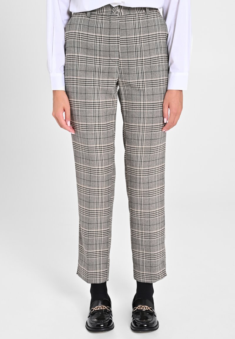 Graue karierte Hose mit maßgeschneidertem Schnitt, aus strukturiertem Stoff und mit Knopfverschluss. Kombiniert mit schwarzen Mokassins und Socken.