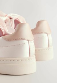 Baskets en satin rose avec une texture lisse, des languettes arrière arrondies et une semelle en caoutchouc blanc solide. Détails de couture sur les côtés et les talons.