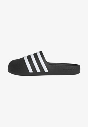 Sandale noire en caoutchouc texturé, ornée de trois rayures blanches parallèles sur le dessus et d'un logo sur le côté.