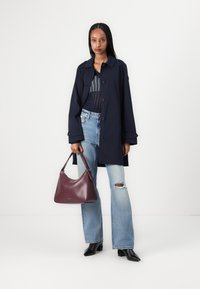 Marineblå frakk med krage og knappelukking, blåmønstret topp, lyseblå ripped jeans og en burgunder lærveske. Svarte spisse hæler.