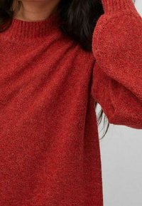 Czerwony sweter dziany z okrągłym dekoltem i ściągaczami na rękawach, o miękkiej fakturze i lekko luźnym kroju.