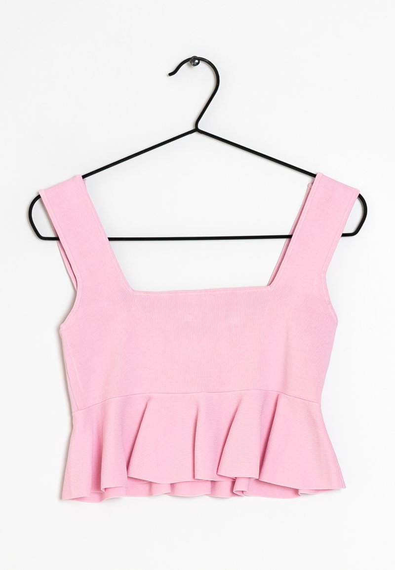 Roze peplumtop van ribstof. Vierkante halslijn, brede bandjes en uitlopende zoom. Hangt aan een zwarte metalen hanger.