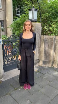 Body negru cu mânecă lungă și decolteu pătrat, pantaloni negri cu talie înaltă și adidași vișinii. Accesoriu: mică geantă neagră.