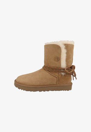 Tan suède enkelboots met een pluizige witte voering en een bruine rubberen zool. Voorzien van een gevlochten koordaccent rond de hak.