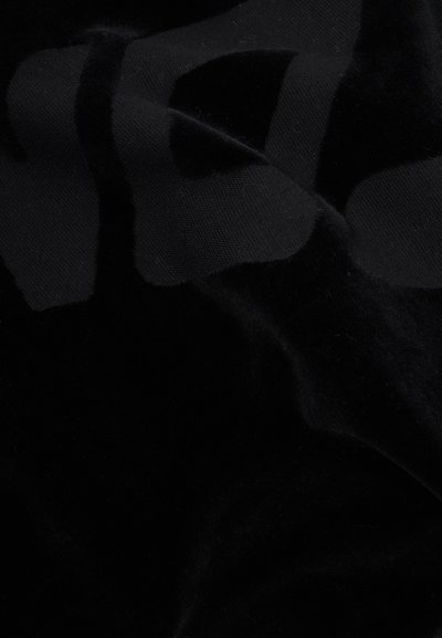 Juodas audinys su minkšta, tekstūruota paviršiumi. Yra subtilus raštas skirtingose juodos ir tamsiai pilkos spalvose. Raukšlėta išvaizda.