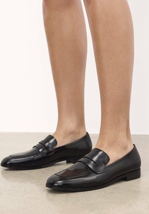 Zwarte leren loafers met een glanzende afwerking, met een ronde neus, instapontwerp, kleine hak en tonale stikdetails.
