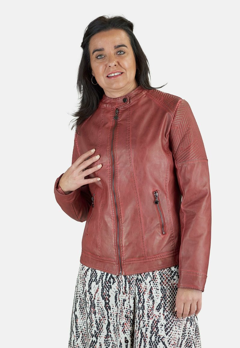 Chaqueta de cuero roja con cuello alto, cierre delantero con cremallera y bolsillos laterales. Los hombros texturizados añaden interés visual.