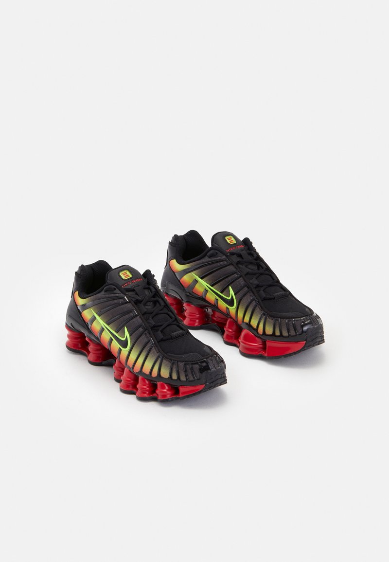 Mustat Nike-tennarit, joissa on keltaisen, vihreän ja punaisen värin gradienttikoristeet. Varustettu erityisellä tekstuuripinnalla ja paksulla punaisella pohjalla.