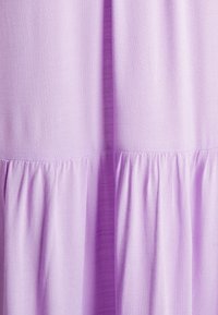 Tecido de vestido lilás claro com acabamento texturizado, apresentando detalhes de franzido na bainha e costuras verticais suaves para maior estrutura.