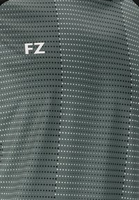 Kortärmad sporttröja i mörkgrått med ett mönster av svarta och vita prickar i olika storlekar. Har FZ-logotypen i vitt på vänster sida.