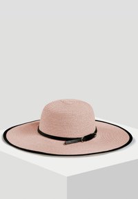 Szerokoskrzydły słomkowy kapelusz w jasnoróżowym kolorze, z czarną wstawką i wykończeniem, o okrągłym plecionym wzorze.