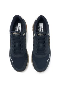 Zapatillas navy con tejido texturizado y acentos de ante. Cuenta con un collar acolchado, cierre de cordones y suela de goma con detalles en marrón claro.