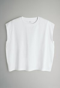 Valkoinen hihaton toppi pyöreällä pääntielle, valmistettu pehmeästä kankaasta. Siinä on lyhyt malli ja hienovaraisesti kaartuva helma.