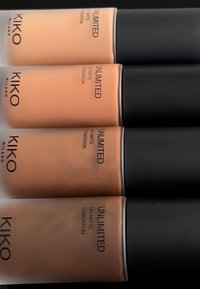 Fire flasker med KIKO Milano Unlimited 24H Matte Foundation i ulike nyanser av beige og brun, med svarte hetter og etiketter som viser produktopplysninger.