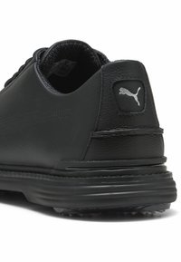 Melnas ādas sporta kurpes ar strukturētu virsmu, noapaļotu formu, mīkstu apakšmalu un gumijas zoli ar mazām naglām. Ietver Puma logo uzlīmi.