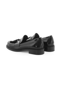 Schwarze Leder-Tassel-Loafers mit niedrigen, gestapelten Absätzen und detaillierter Stickerei entlang der Sohle, vor einem weißen Hintergrund präsentiert.