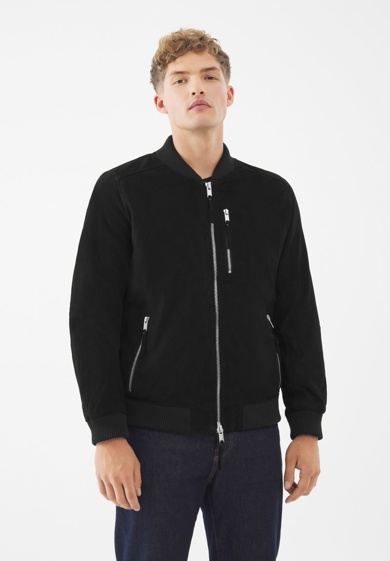 Svart bomberjacka med texturerad yta, featuring en ficka med dragkedja framtill, två sidofickor med dragkedjor och ribbade mudd och nederkant.