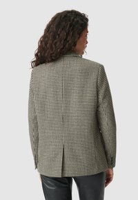 Blazer a motivo cavallo di battaglia in bianco e nero, con spalle strutturate, apertura centrale sul retro e vestibilità sartoriale. Tessuto liscio, con dettagli di bottoni.