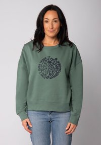 Sweatshirt vert à col rond et manches longues. Présente un imprimé graphique d'un cerveau et de fleurs, avec le texte "NE PAS TROP RÉFLÉCHIR."