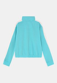 Sweatshirt cropped de manga longa em turquesa com colarinho alto e riscas brancas e pêssego ao longo das mangas.