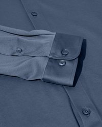 Polsino abbottonato e manica di una camicia a maniche lunghe liscia, di un colore solido, che mostra tre bottoni sul polsino e due sulla manica.