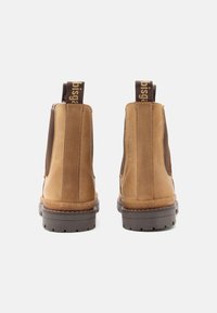 Bottines Chelsea en cuir marron avec des panneaux latéraux élastiques, deux tirants et une semelle en caoutchouc robuste avec un motif de semelle texturé.