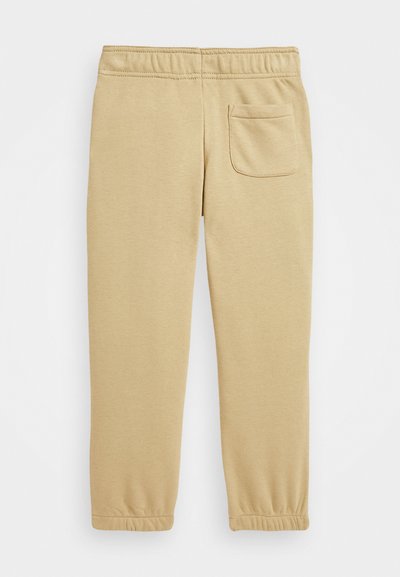 Pantalones jogger de algodón beige con cintura elástica, puños ajustados y un bolsillo trasero para almacenamiento. Textura suave en toda la prenda.